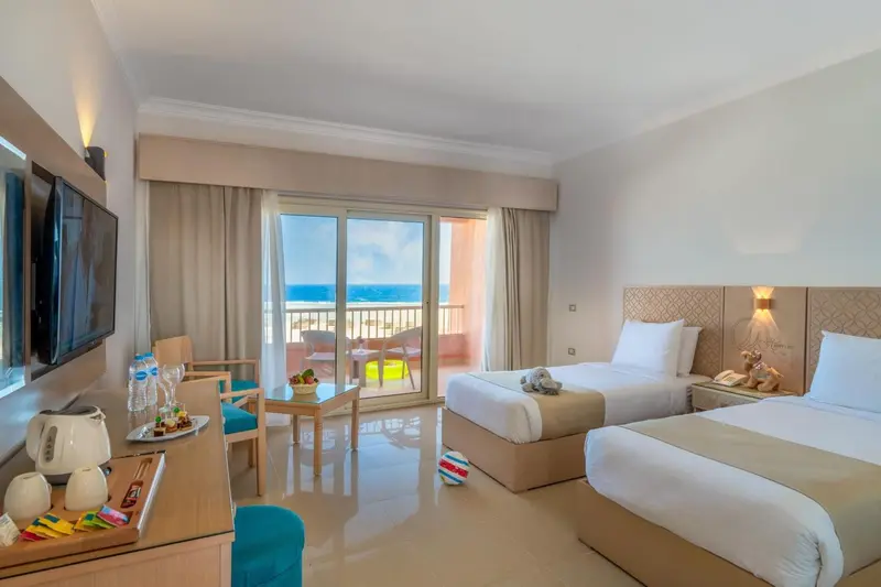 Chambre lumineuse avec vue sur la mer depuis un balcon.