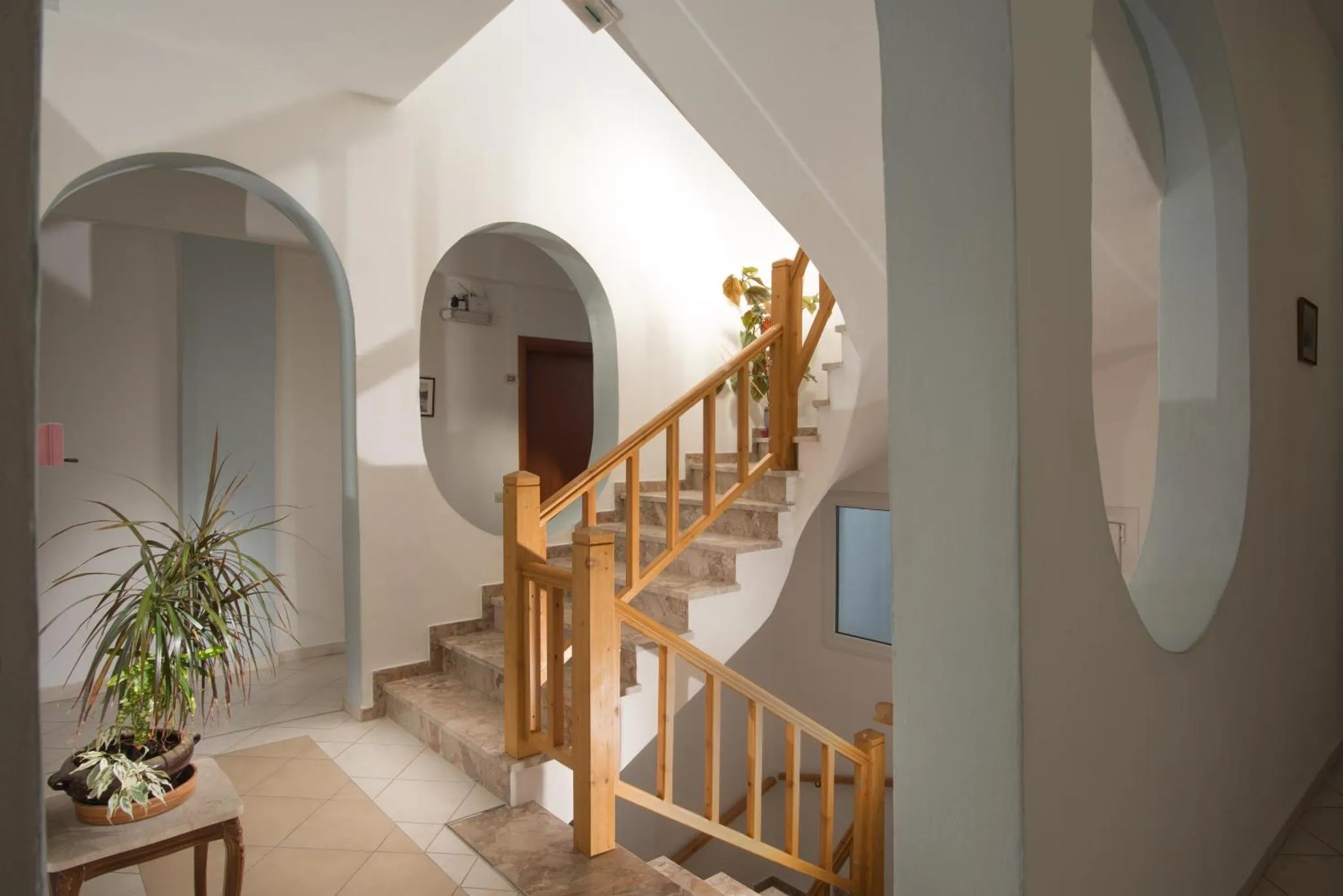 Un escalier en bois mène à l'étage supérieur dans un intérieur clair et épuré.