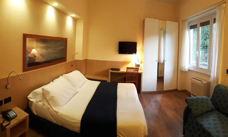 Une chambre lumineuse avec un lit double et un coin salon.