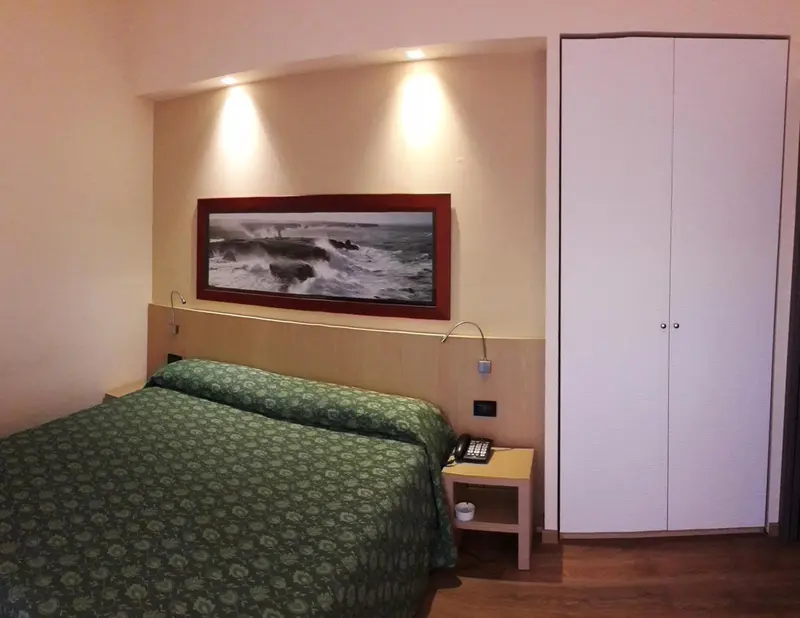 Une chambre à coucher avec un lit recouvert d'une couette verte et une décoration murale représentant une scène marine.