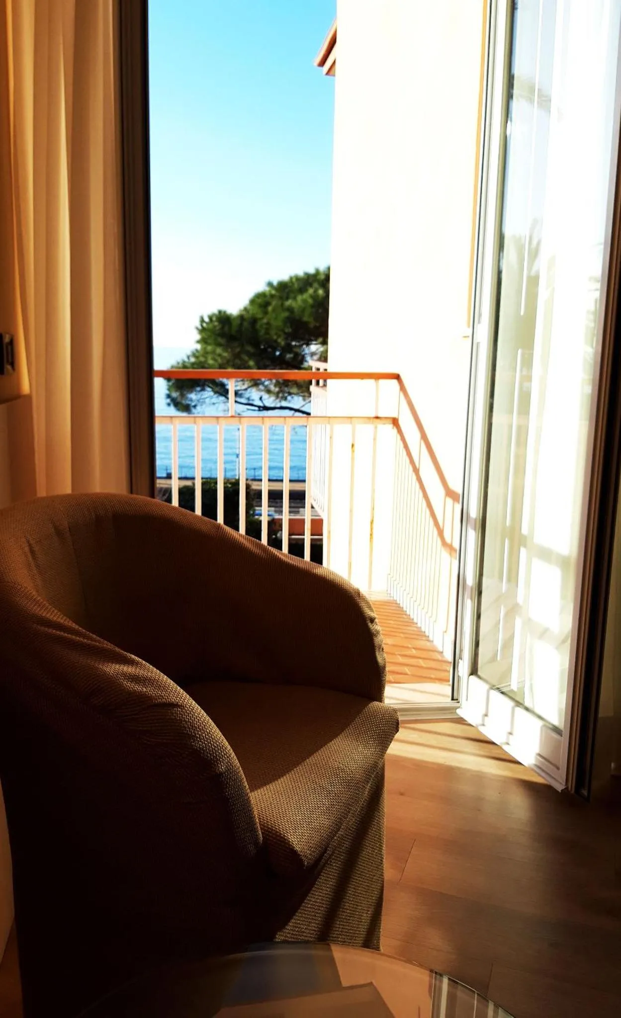 Un fauteuil confortable se trouve sur une terrasse ensoleillée avec vue sur la mer.