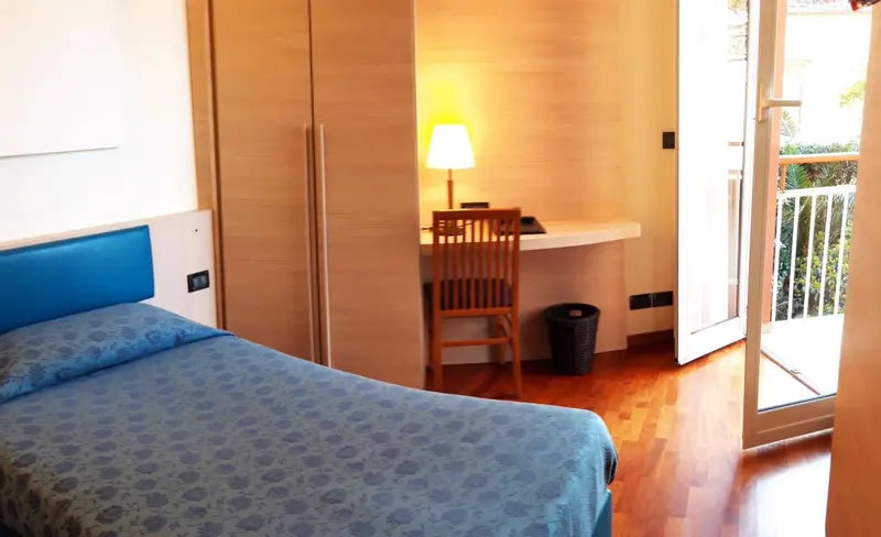 Une chambre lumineuse avec un bureau et une porte-fenêtre donnant sur l'extérieur.
