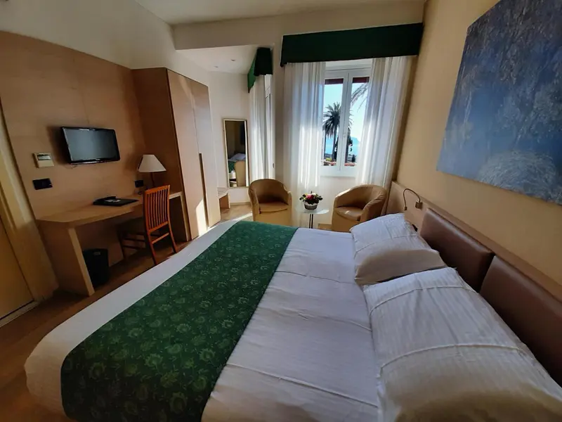 Une chambre lumineuse avec un grand lit et un bureau près de la fenêtre.