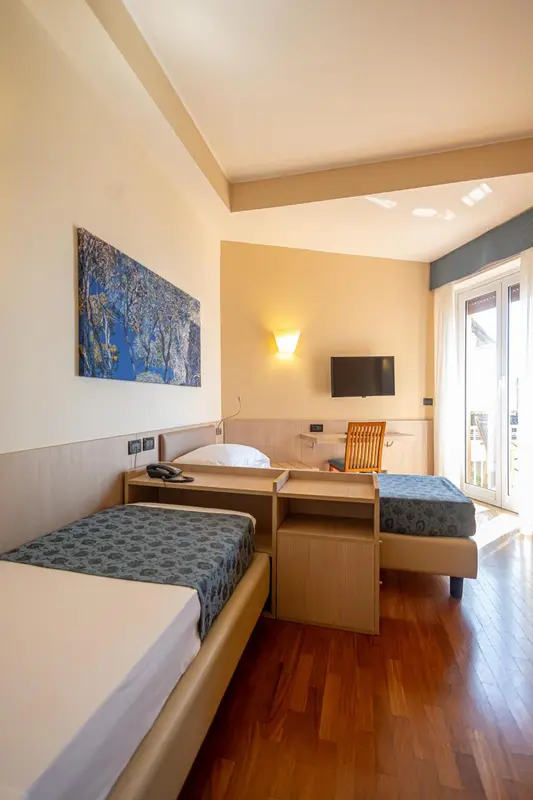 Une chambre lumineuse avec deux lits simples et un accès à une terrasse.