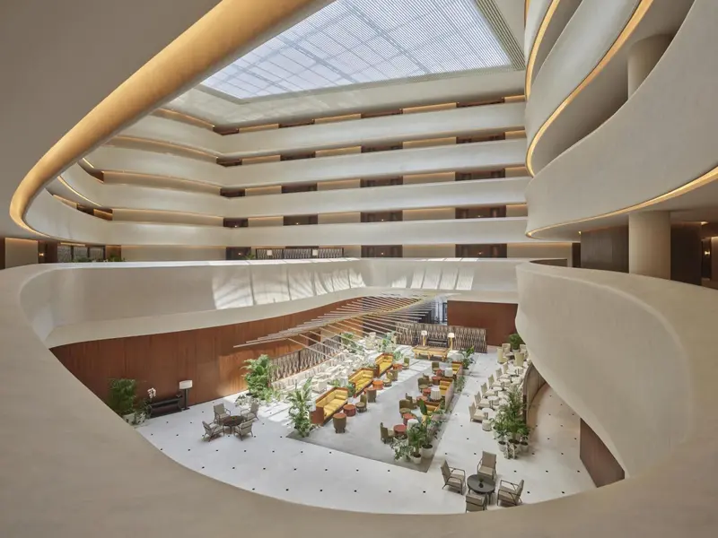 Vue d'intérieur d'un hall d'hôtel avec un jardin central et des galeries.