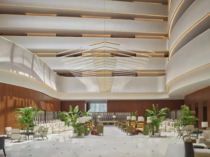 Vaste hall d'accueil avec mobilier contemporain et plantes tropicales.