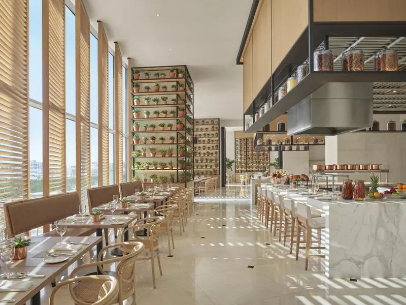 Une salle lumineuse avec des tables dressées et un comptoir de buffet.