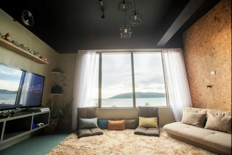 Un salon lumineux avec canapés et vue sur la mer par de grandes fenêtres.