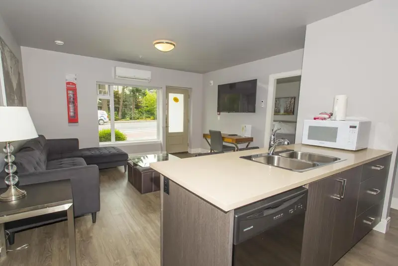 Espace de vie lumineux avec canapé, cuisine équipée et télévision à écran plat.