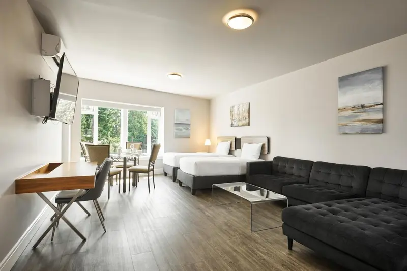 Espace de vie lumineux avec canapé, table basse et espace repas près de la fenêtre.