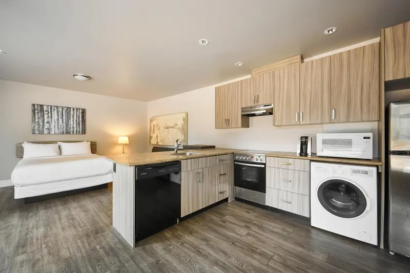 Une cuisine moderne s'ouvre sur un espace de repos avec un lit.