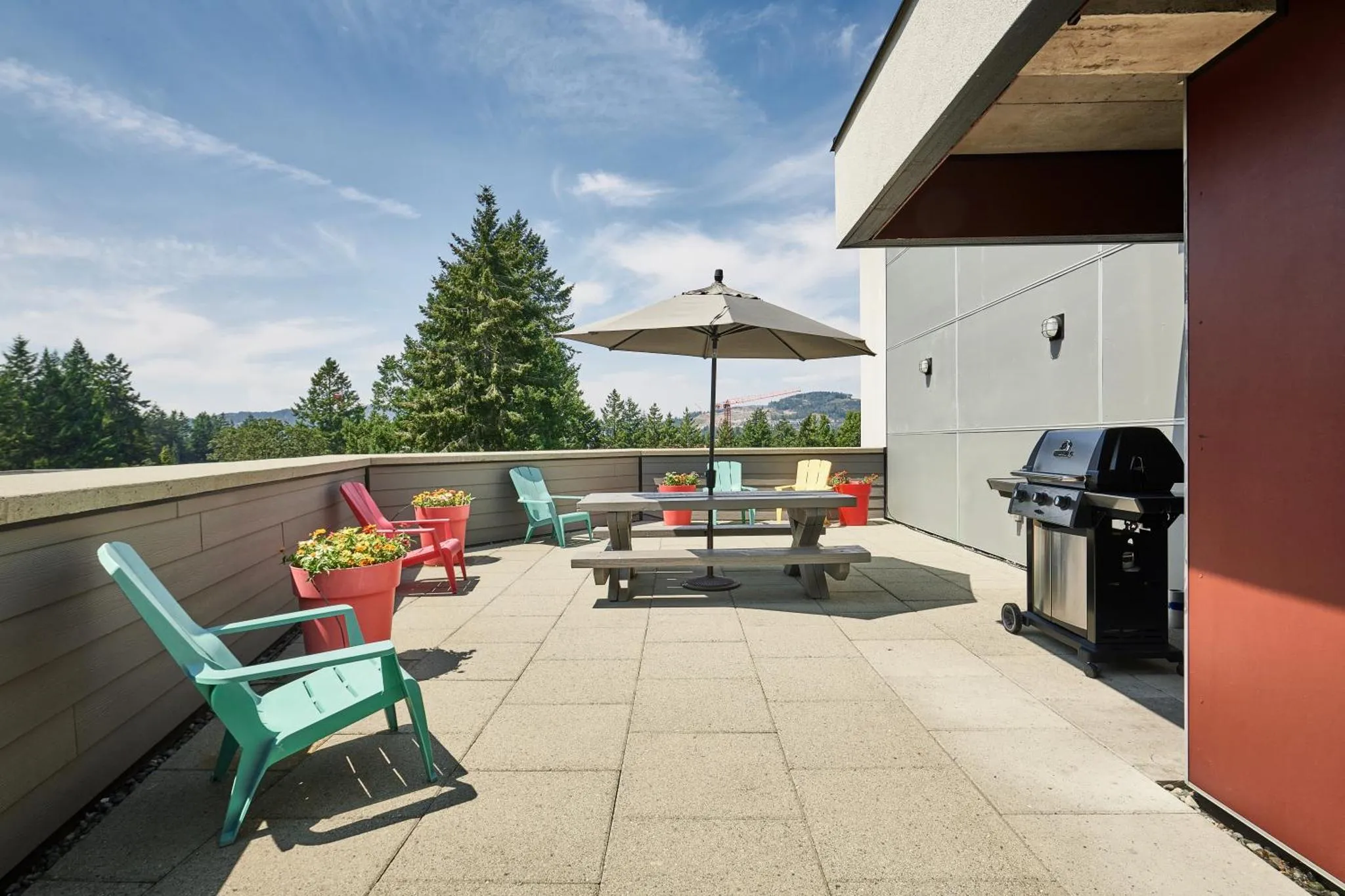 Terrasse aménagée avec mobilier de jardin et barbecue, offrant une vue sur la végétation.