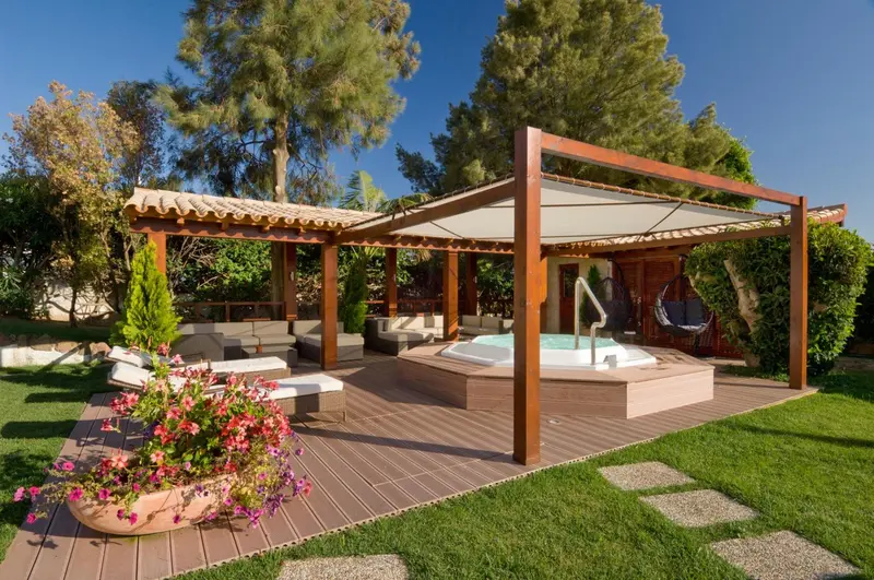 Espace de détente extérieur avec jacuzzi et mobilier de jardin.