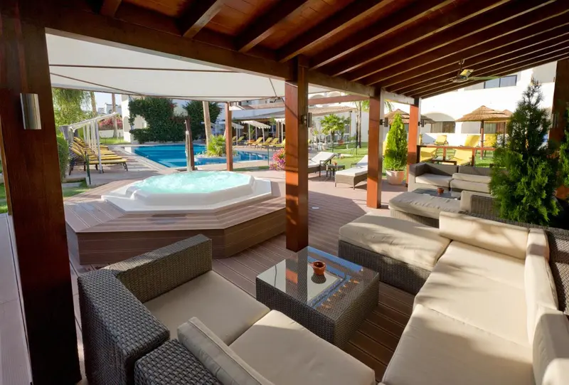 Espace de détente extérieur avec mobilier confortable et jacuzzi.