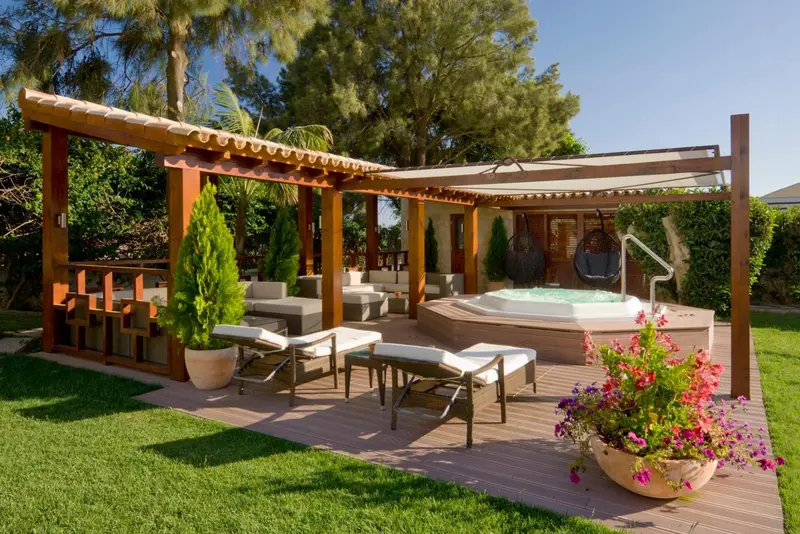 Espace de détente extérieur avec jacuzzi et mobilier de jardin.