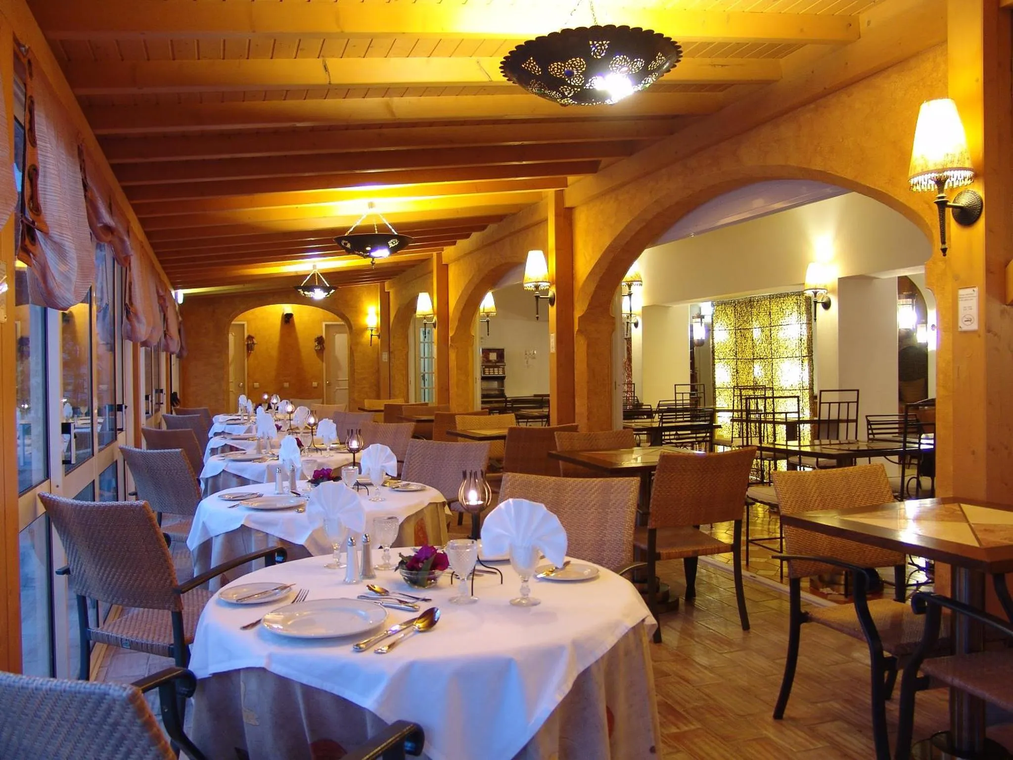 Une salle lumineuse avec des tables dressées pour un repas.