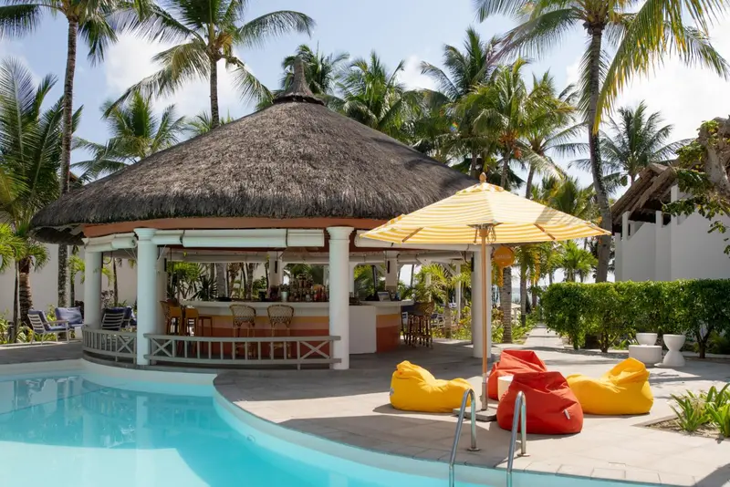 Un bar de plage ombragé par un parasol et un toit de chaume.