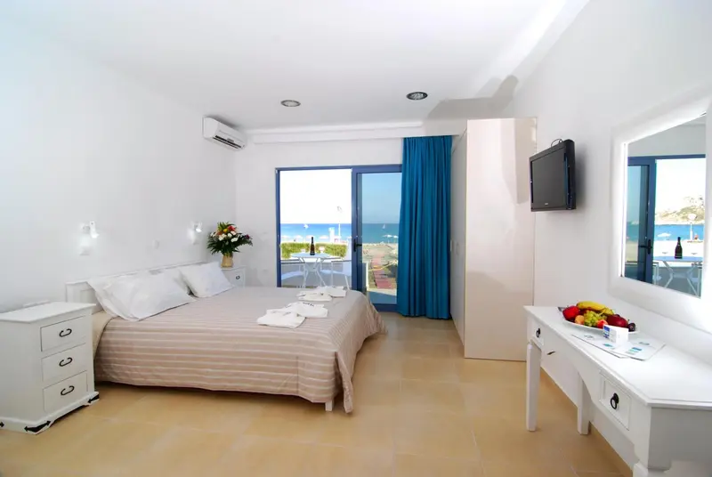 Chambre lumineuse avec un grand lit et vue sur la mer.