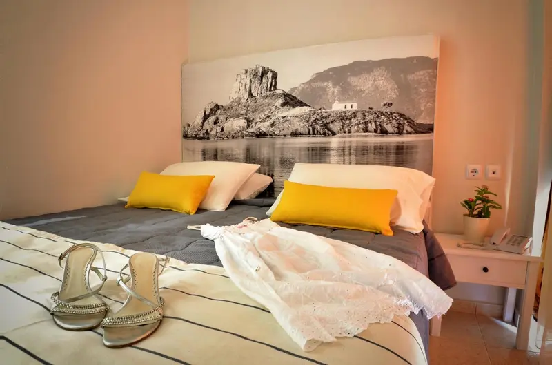 Une chambre lumineuse avec un grand lit et une décoration murale représentant un paysage marin.
