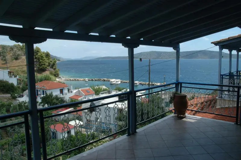 Terrasse ombragée donnant sur une vue côtière et des bâtiments.