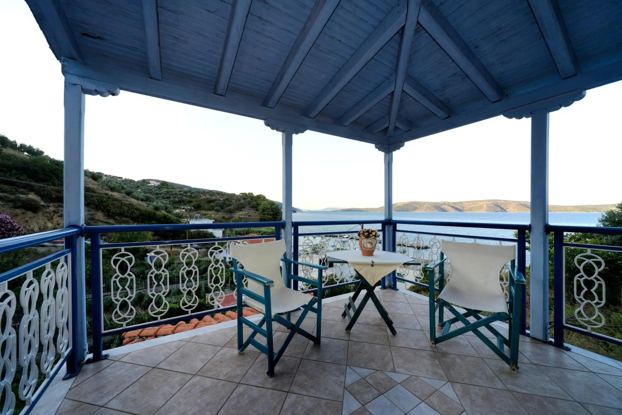 Terrasse ombragée avec table et chaises donnant sur la mer.