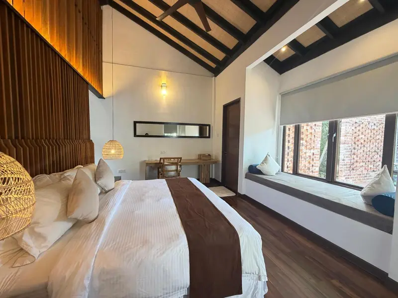 Une chambre lumineuse avec un grand lit et un coin lecture près de la fenêtre.