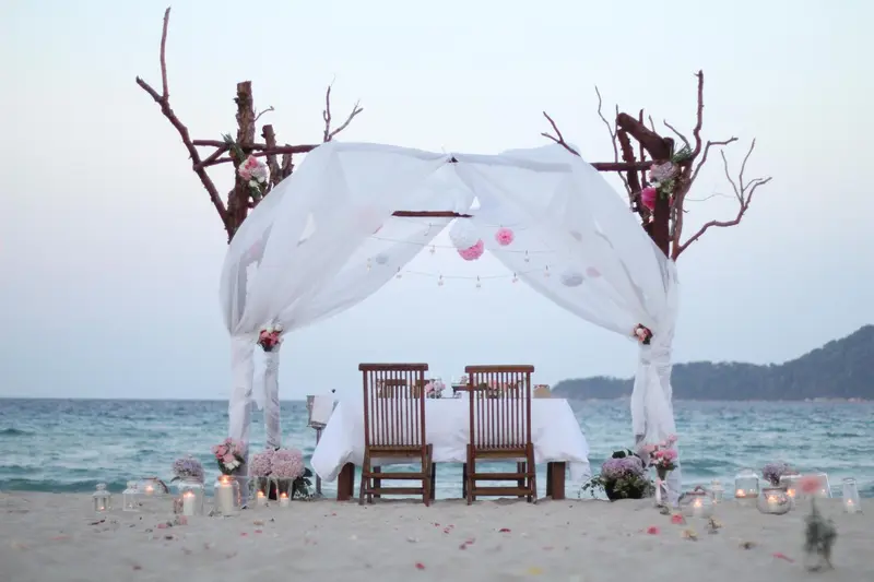 Table dressée pour un dîner romantique sur une plage de sable fin.