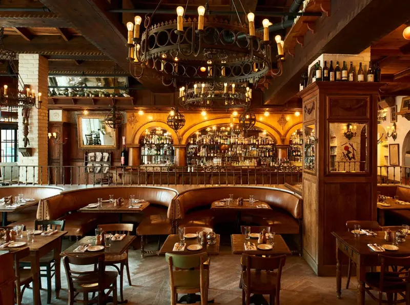 Une salle de restaurant chaleureuse avec des tables et des banquettes en bois.