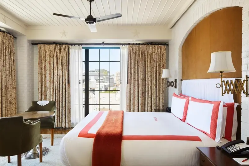Une chambre lumineuse avec un lit double et un coin repas près d'une fenêtre.