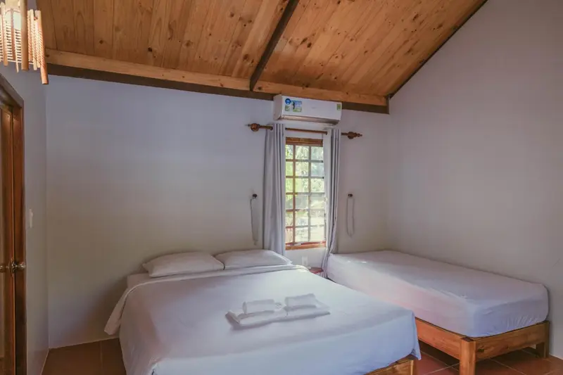 Une chambre lumineuse avec deux lits simples et une fenêtre.