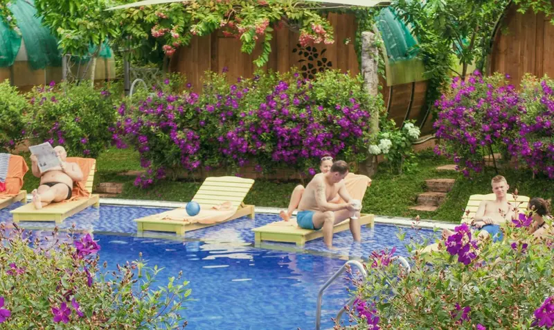 Des transats colorés bordent une piscine turquoise entourée de végétation luxuriante.