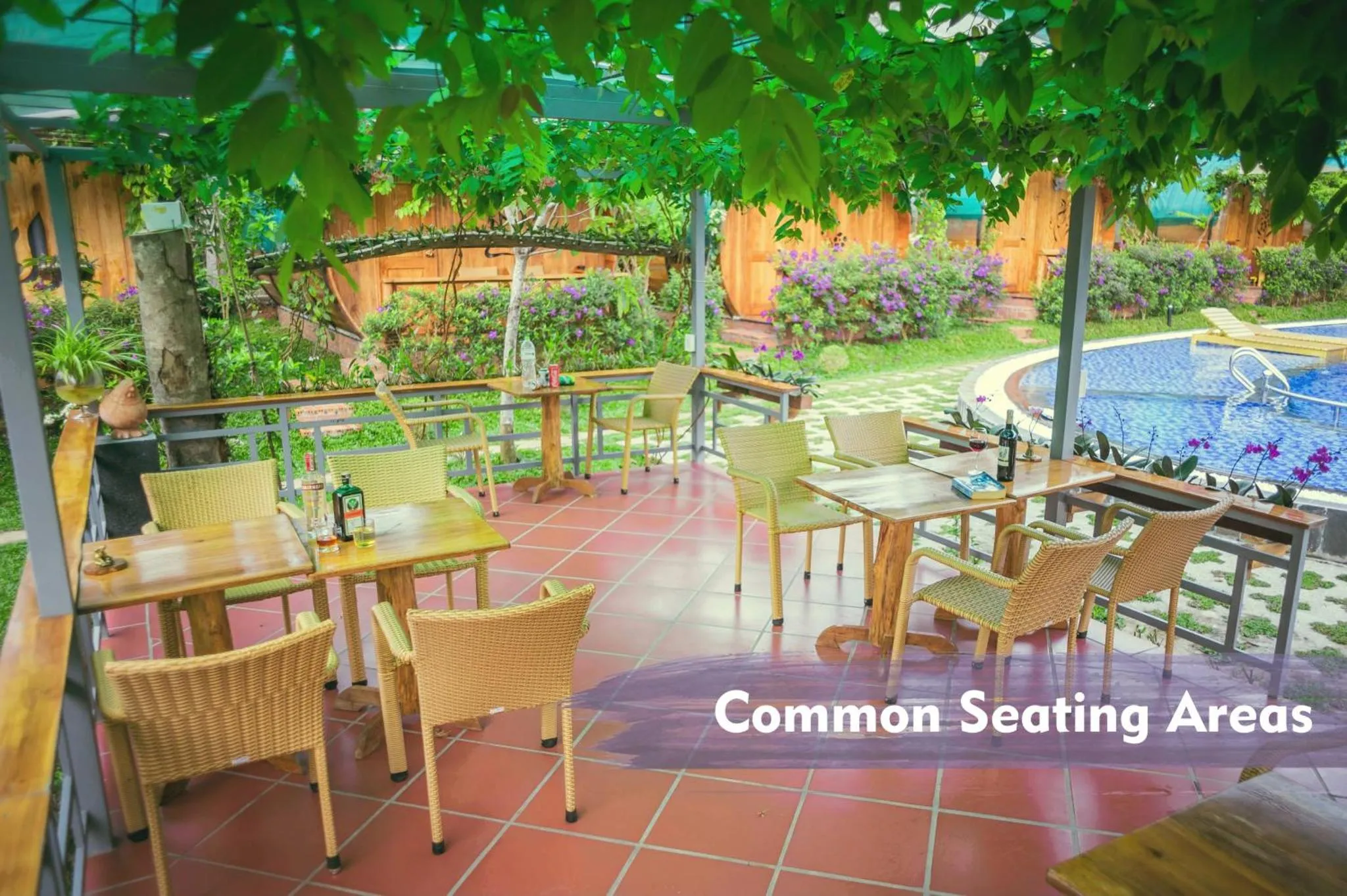 Terrasse ombragée avec tables et chaises près d'une piscine.