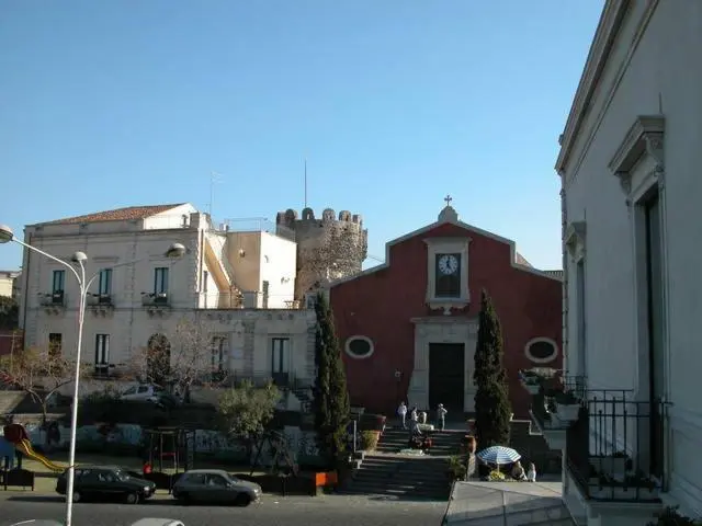Bâtiments blancs et rouges avec une église et une tour, sous un ciel bleu.