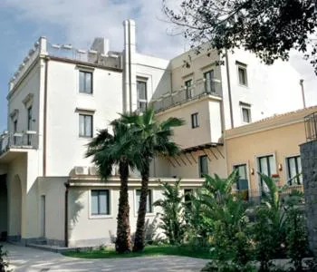Bâtiment blanc à plusieurs étages avec des balcons et une végétation tropicale.