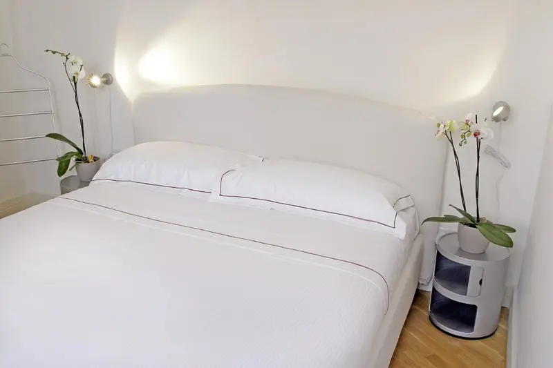 Lit blanc immaculé dans une chambre lumineuse et minimaliste.