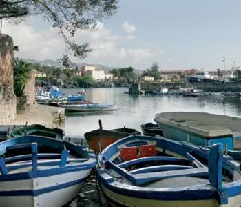 Plusieurs petites embarcations colorées sont amarrées dans un port abrité.