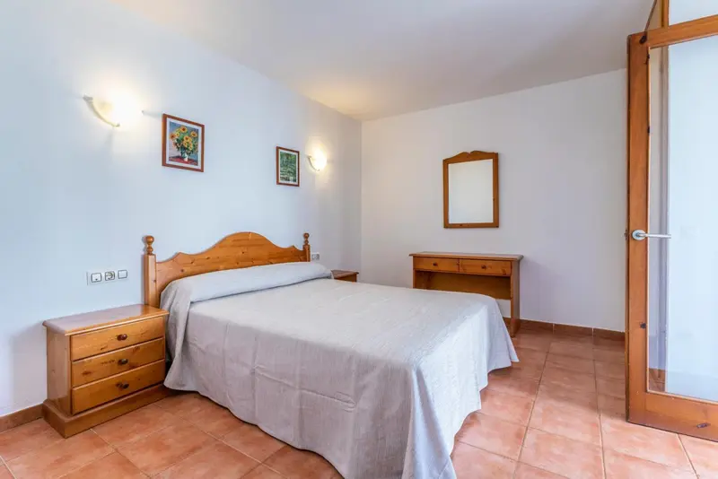 Une chambre lumineuse avec un lit double et des meubles en bois.