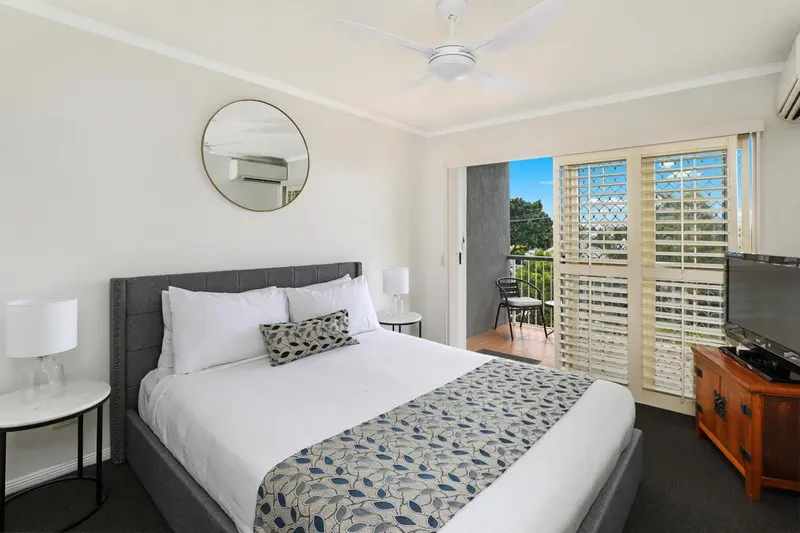 Une chambre lumineuse avec un grand lit et un accès à un balcon.