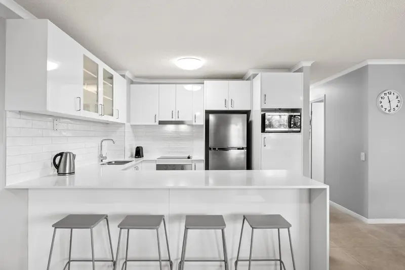 Cuisine moderne et lumineuse avec un îlot central et des tabourets.