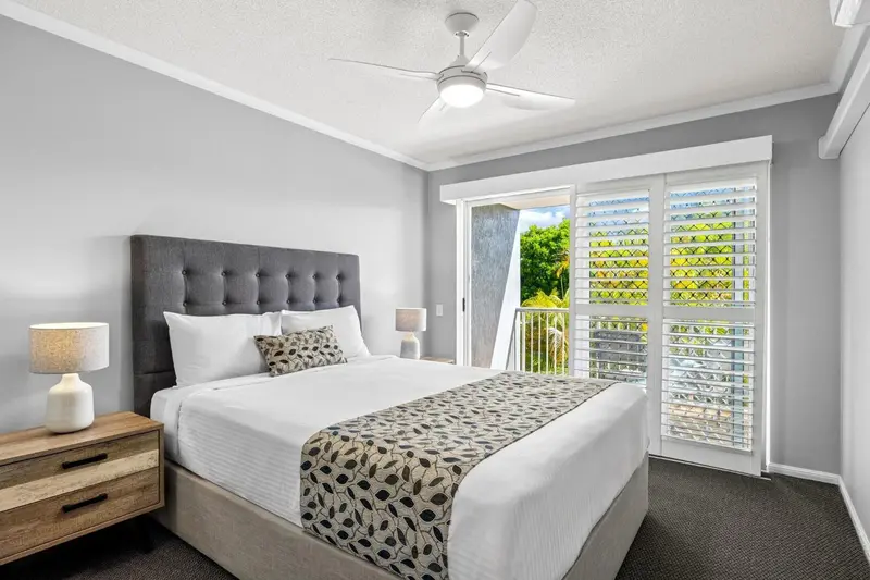 Une chambre lumineuse avec un grand lit et des rideaux blancs.