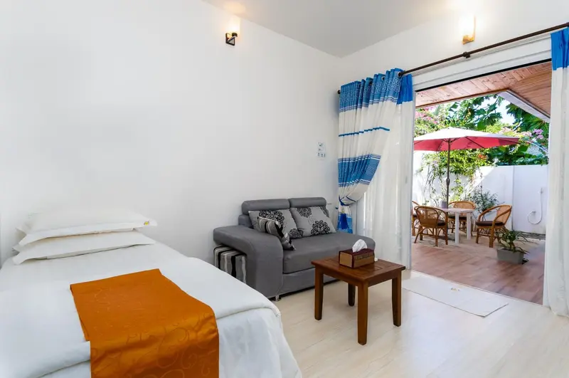 Une chambre lumineuse s'ouvre sur une terrasse avec mobilier de jardin.