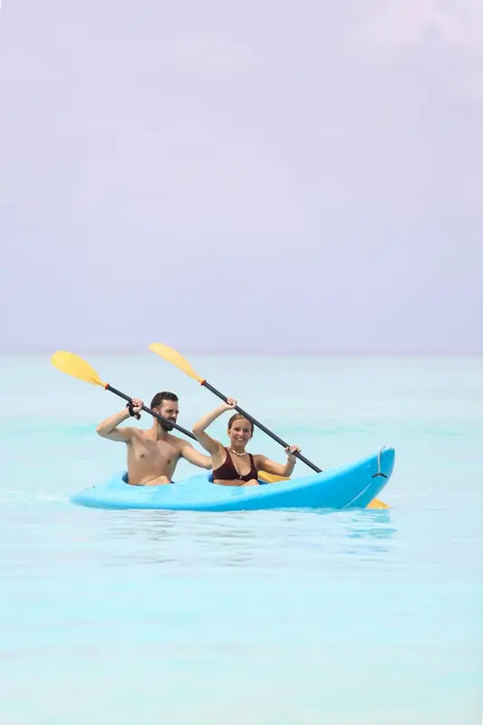 Un couple pratique le kayak sur une eau turquoise et calme.