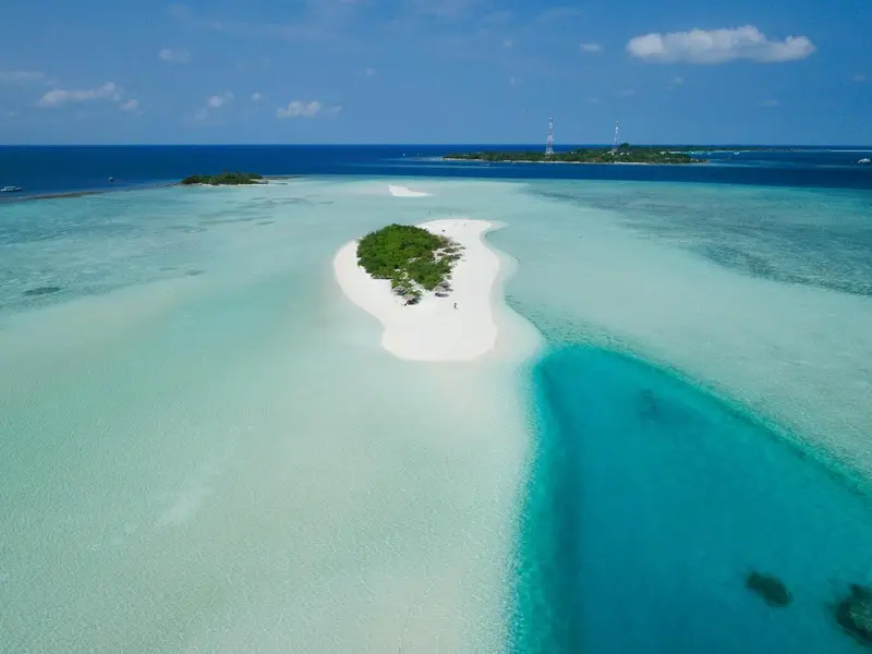 Vue aérienne d'une île tropicale entourée d'eaux turquoise et de bancs de sable.