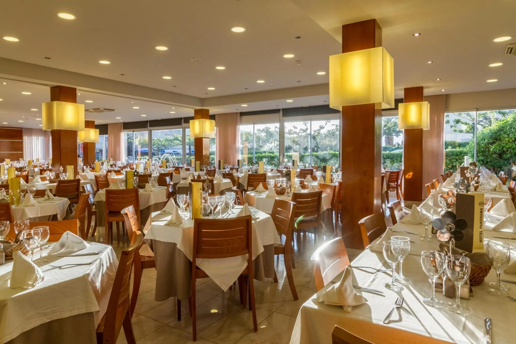 Une salle lumineuse avec des tables dressées pour un repas.