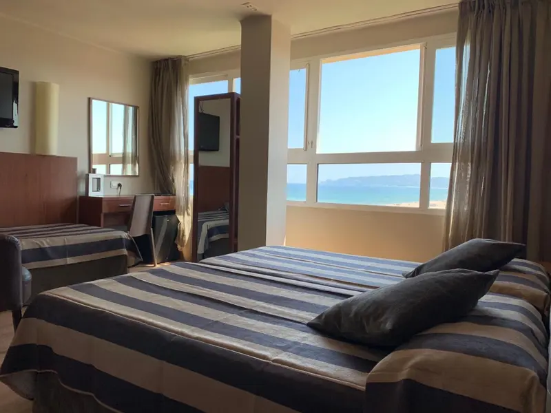 Chambre avec lits jumeaux et vue sur la mer par de grandes fenêtres.