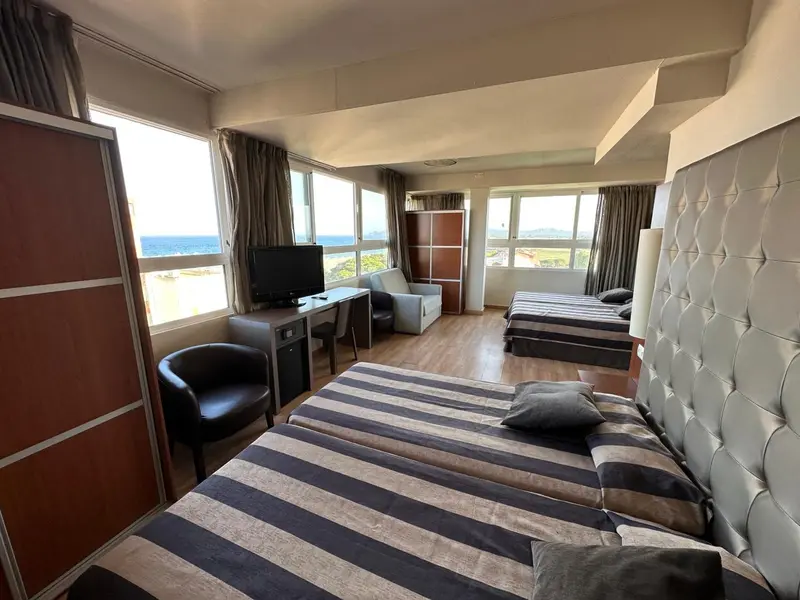 Une chambre d'hôtel lumineuse avec deux lits et un coin salon.