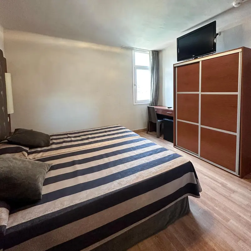 Une chambre avec un grand lit et un placard en bois.