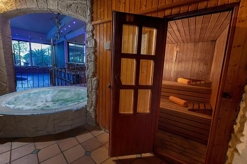 Une porte en bois s'ouvre sur un espace de sauna en bois clair.