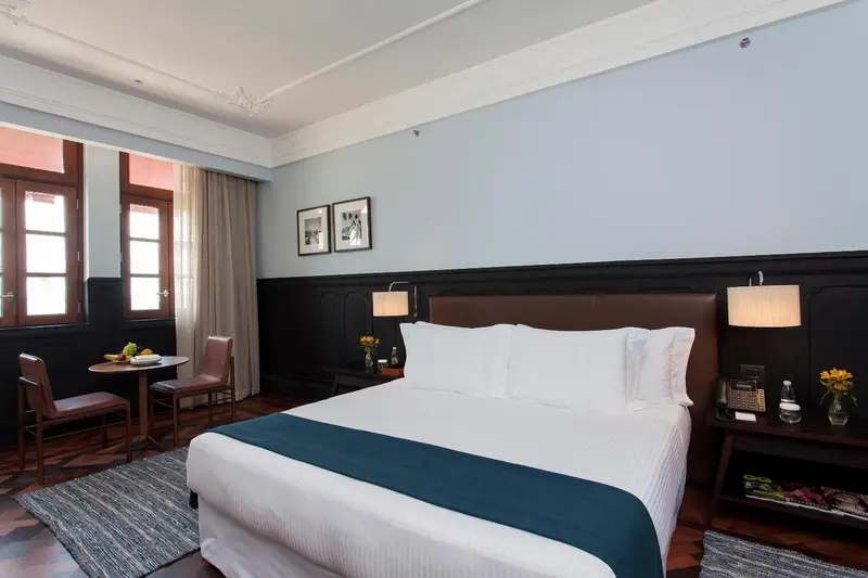 Une chambre d'hôtel lumineuse avec un lit double et un coin repas.