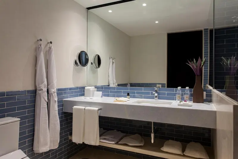Une salle de bain moderne avec un grand miroir et des carreaux bleus.